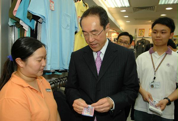 唐英年向鯉魚門廣場內一間服裝店店員介紹新香港拾元塑質鈔票。