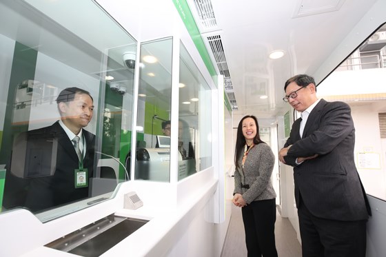 Ms. Louisa Cheang (middle), Vice-Chairman and Chief Executive of Hang Seng Bank, introduces the design and services of the mobile branch to Mr. Norman Chan (right), Chief Executive of the HKMA.
