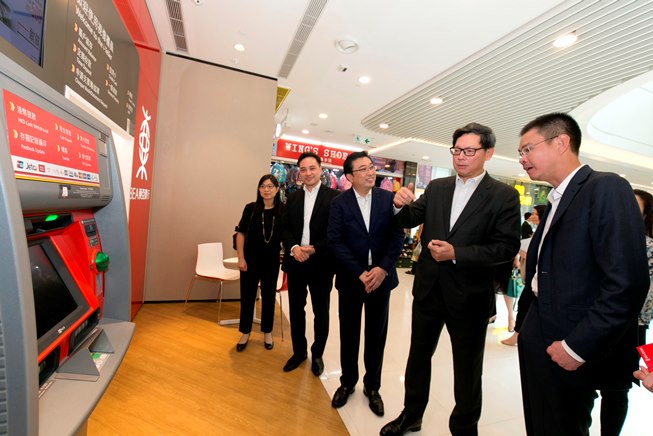 东亚银行执行董事兼副行政总裁李民桥先生（右一）及银行代表向金管局总裁陈德霖先生（右二）介绍无卡自动柜员机提款服务。