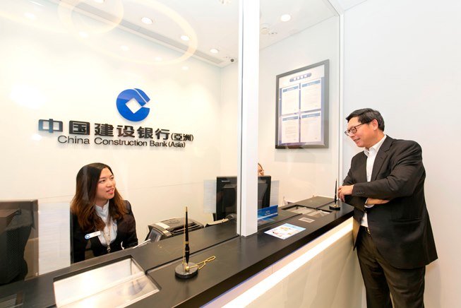 金管局总裁陈德霖先生(右)与中国建设银行（亚洲）的职员交谈，了解分行的服务情况。
