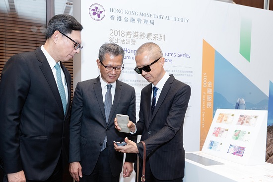 The Financial Secretary of the Government of the Hong Kong Special Administrative Region, Mr Paul Chan, and the Chief Executive of the Hong Kong Monetary Authority (HKMA), Mr Norman Chan, watch a demonstration on identifying the denomination of Hong Kong banknotes by the mobile app “HK$ Reader”.