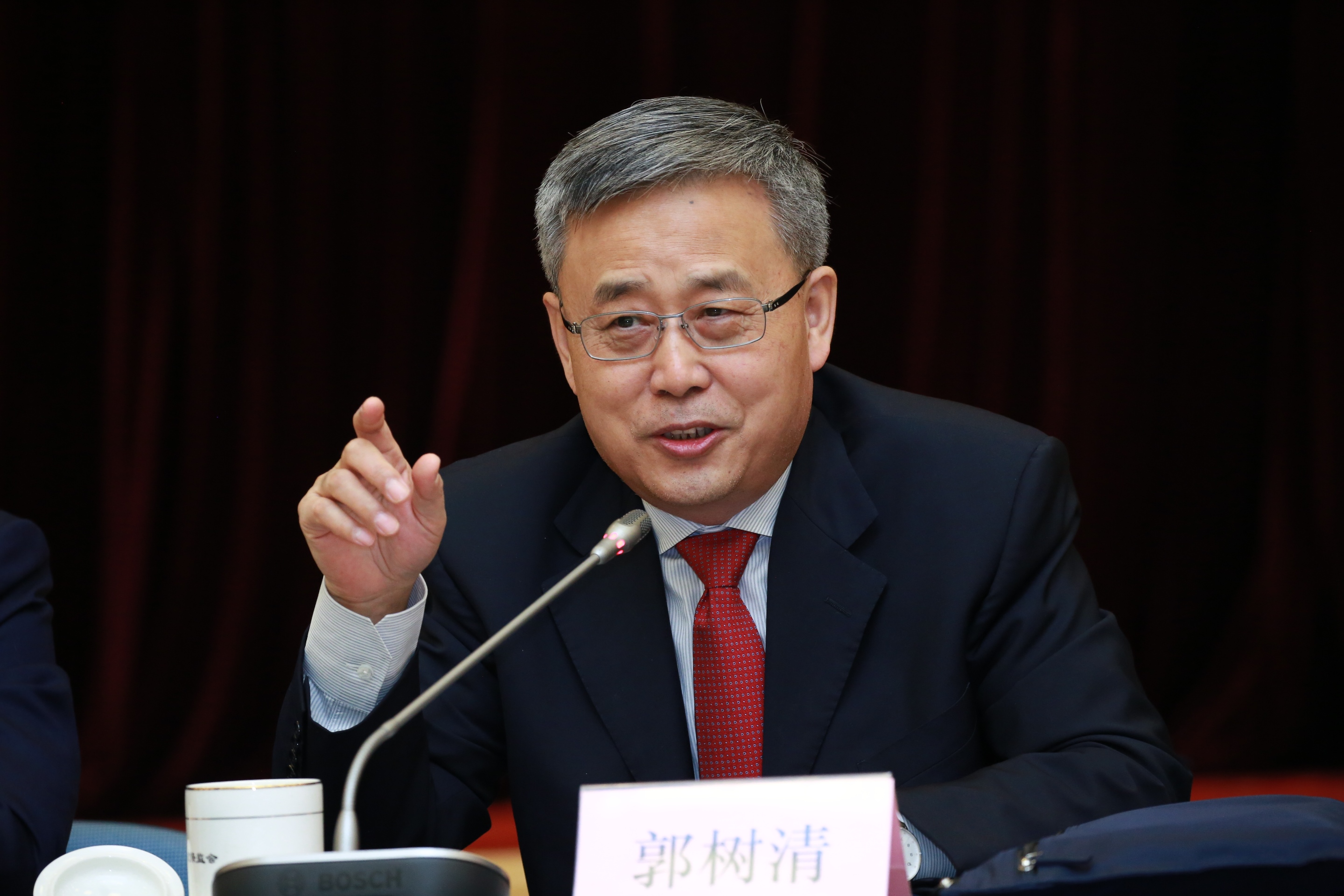 中国银保监会主席郭树清出席座谈会与与会者交流。