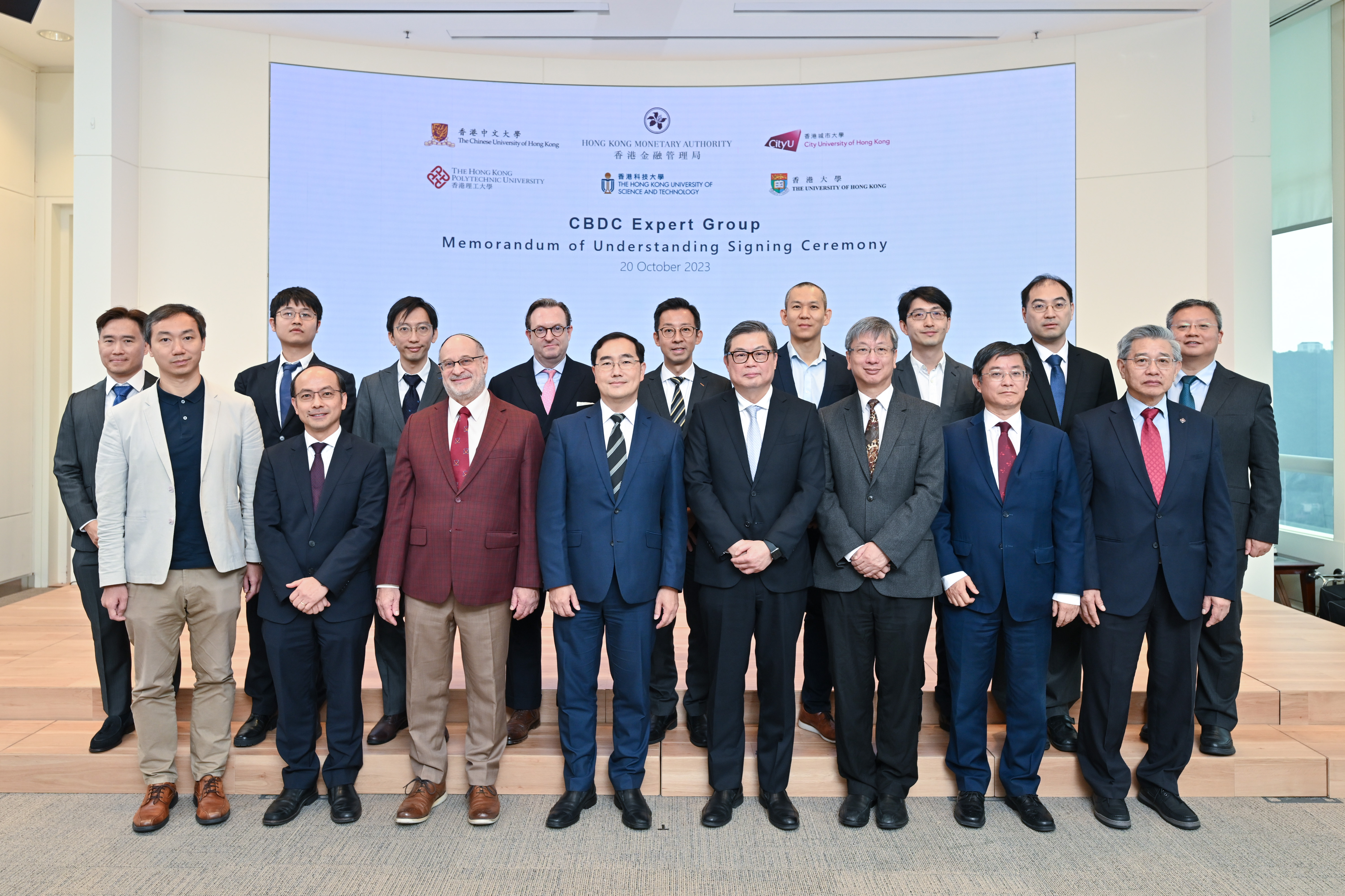 Mr Colin Pou, Executive Director (Financial Infrastructure) of the Hong Kong Monetary Authority (fourth from left, front row), signs Memorandums of Understanding with five local universities whose faculty members are participants of the Central Bank Digital Currency Expert Group