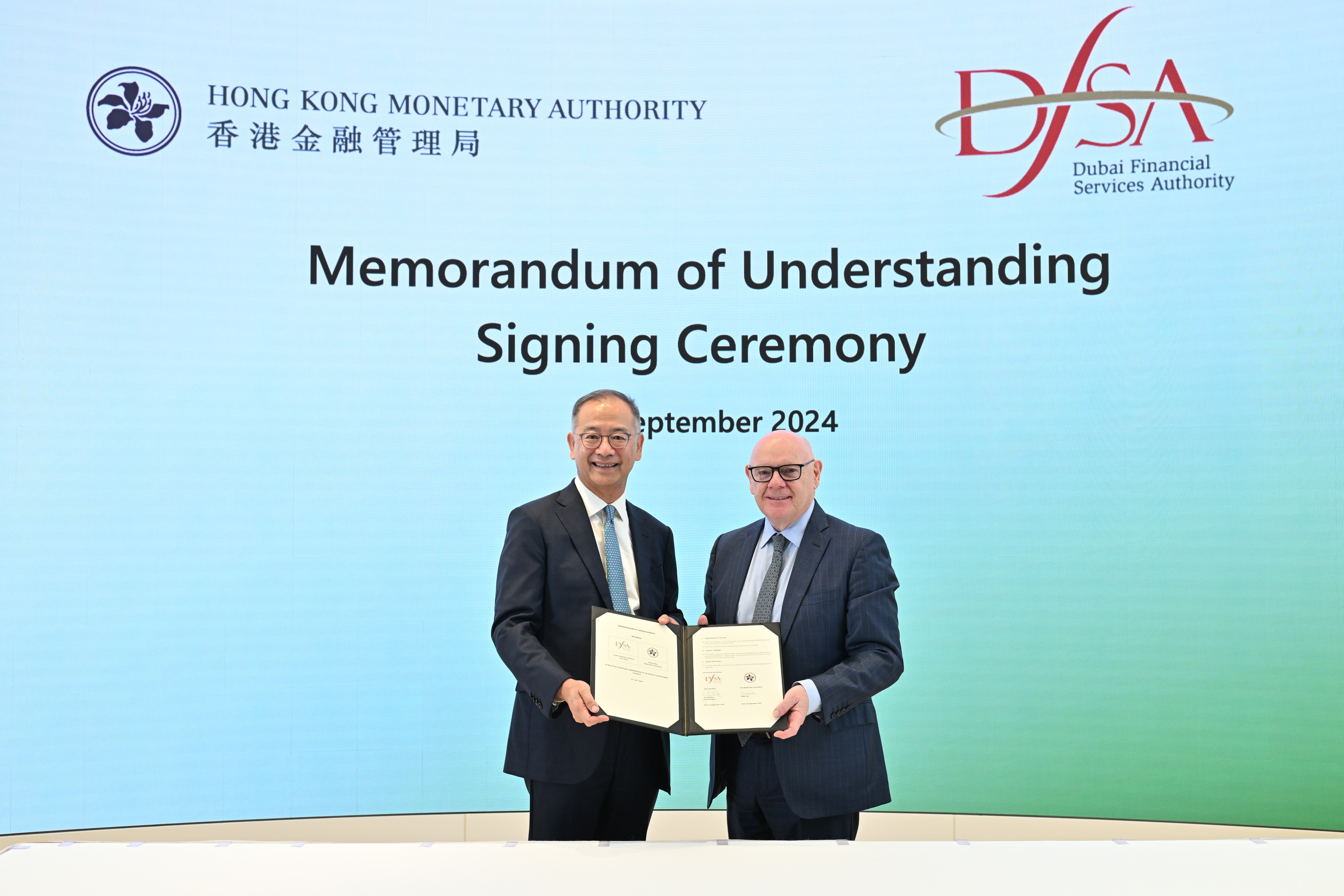 The Chief Executive of the Hong Kong Monetary Authority, Mr Eddie Yue (left), and the Chief Executive of the Dubai Financial Services Authority, Mr Ian Johnston (right), sign and exchange the Memorandum of Understanding in Hong Kong to promote collaboration on sustainable finance.
