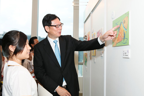 1. 金管局总裁陈德霖与图画创作比赛冠军李艳琴欣赏其得奖作品。