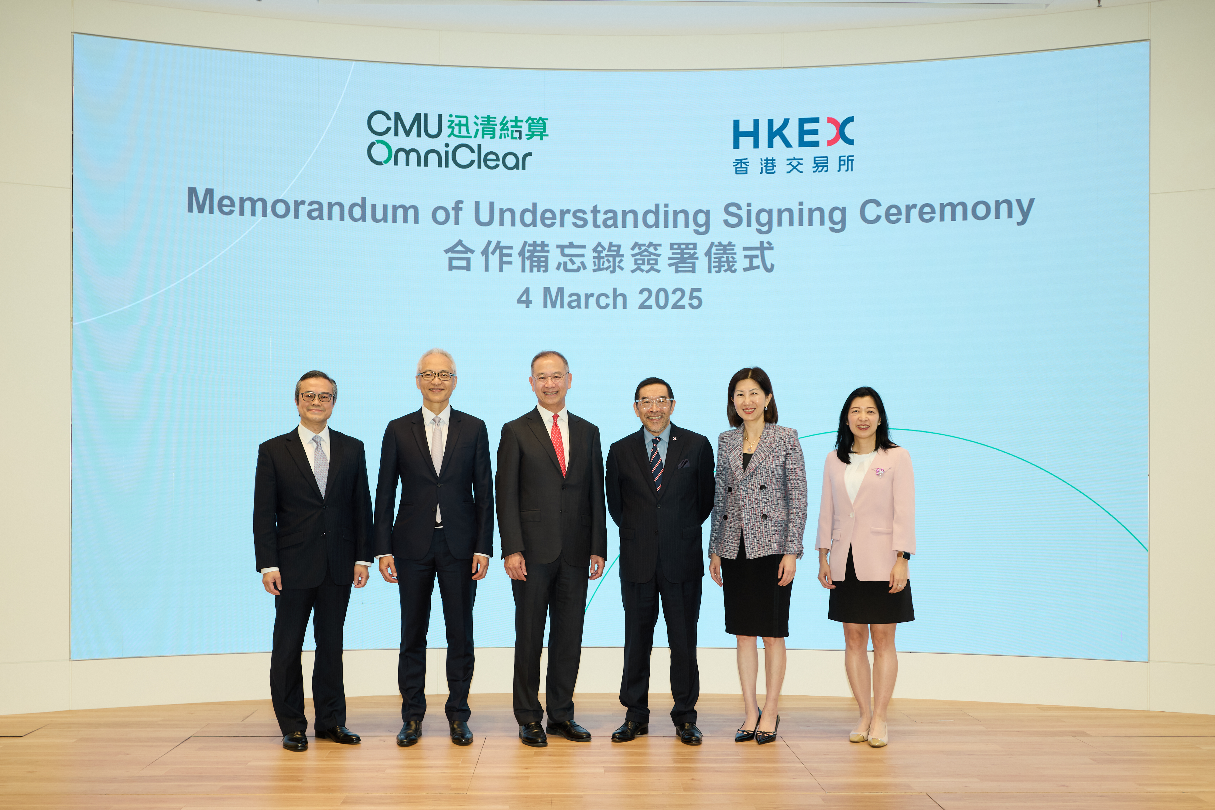 香港金融管理局总裁及迅清结算有限公司董事会主席余伟文（左三）和香港交易及结算所有限公司主席唐家成（右三），在迅清结算有限公司首席执行官陈达强（左一）、香港金融管理局副总裁及迅清结算有限公司董事会副主席李达志（左二）、香港交易及结算所有限公司集团行政总裁陈翊庭（右二）和香港交易及结算所有限公司首席营运总监及集团财务总监刘碧茵（右一）的陪同下出席合作备忘录签署仪式。